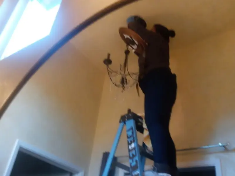 Electrician installing a chandelier in a Brighton residence